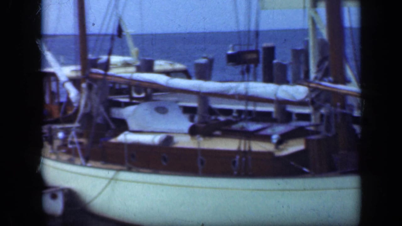 White-hulled sailboat with wooden deck and rigging on calm water.