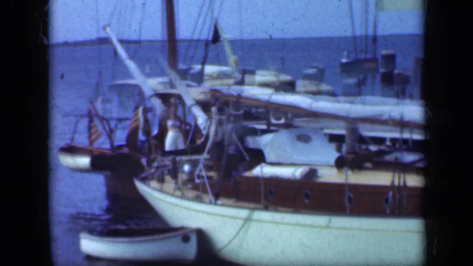 1948 Long Island frame with adults aboard a white-hulled sailboat, including a figure near the stern and another by the cabin area.