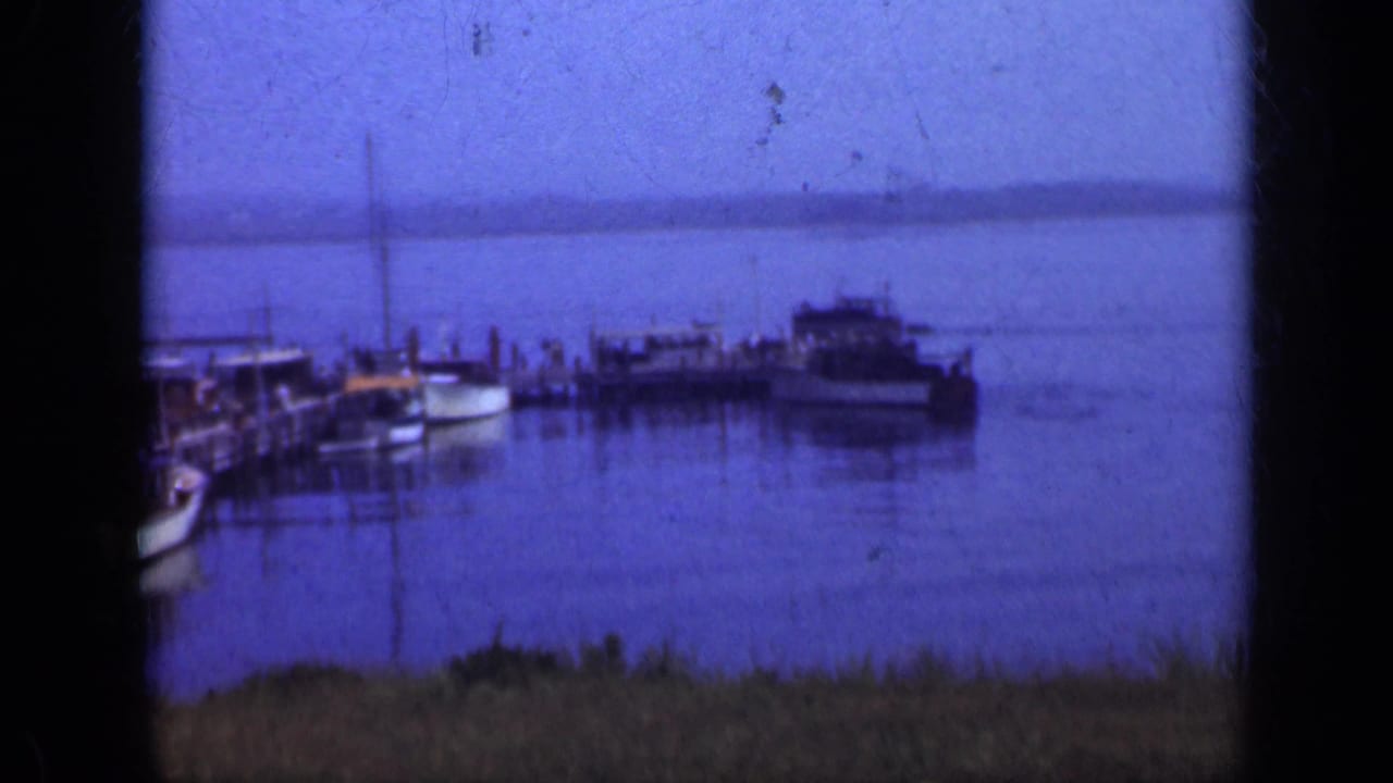 Small boats moored beside a wooden pier on calm blue water.