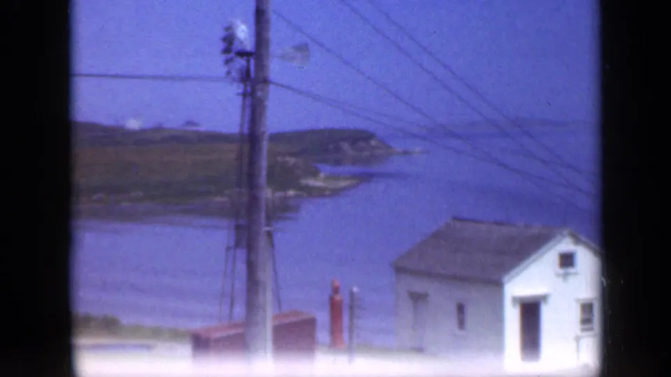 1948 Long Island coastal view with a utility pole, overhead wires, a white house near the water, and a low headland beyond.
