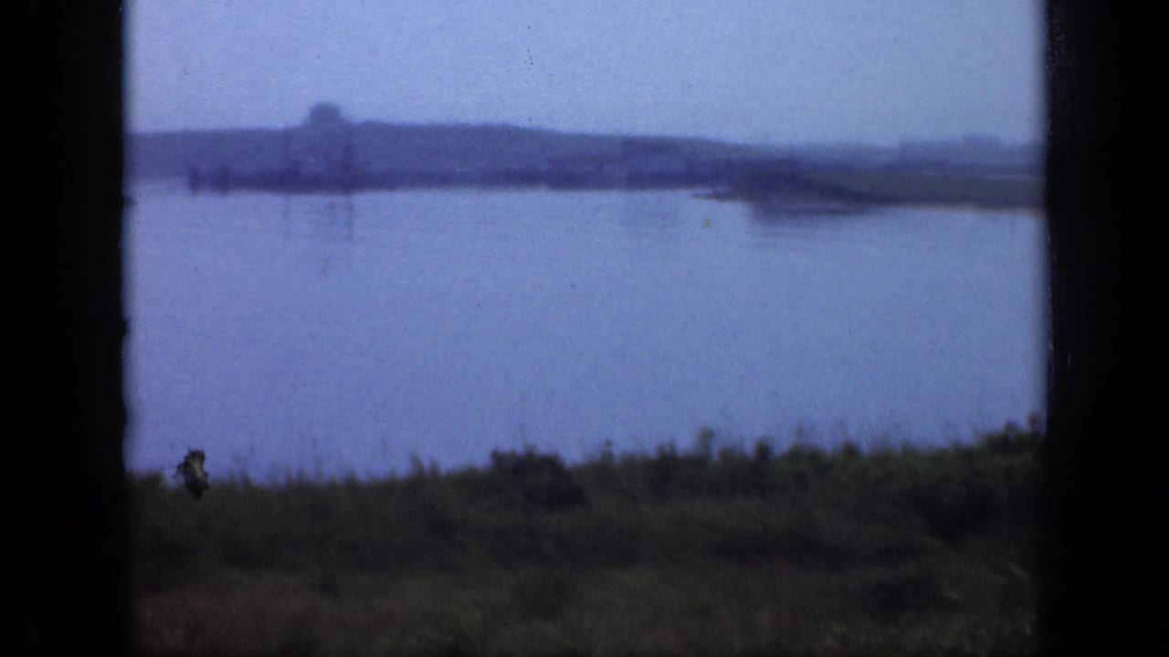 Calm water and distant shoreline framed by dark vertical film borders.