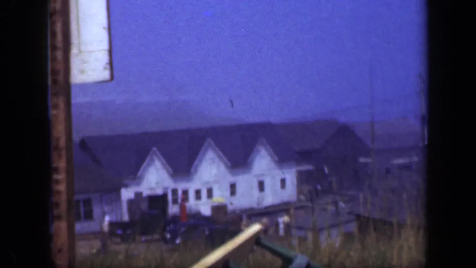 Long Island waterfront buildings and dock structures appear with small distant people near the lower frame, recorded on 8mm in 1948.