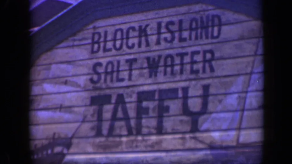 1948 home-movie frame of the Block Island Salt Water Taffy sign, filling most of the frame with visible weathering and soft focus.