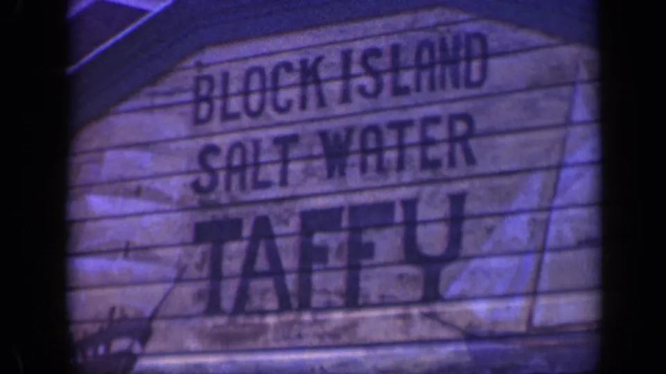 Close 8mm frame of the Block Island Salt Water Taffy sign with faded color, dark gate edges, and hand-painted lettering.