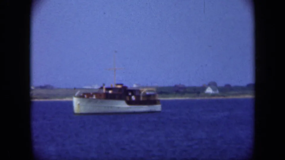 Home-movie view of the motor yacht moving through Long Island coastal water, framed by soft focus and rounded 8mm edges.