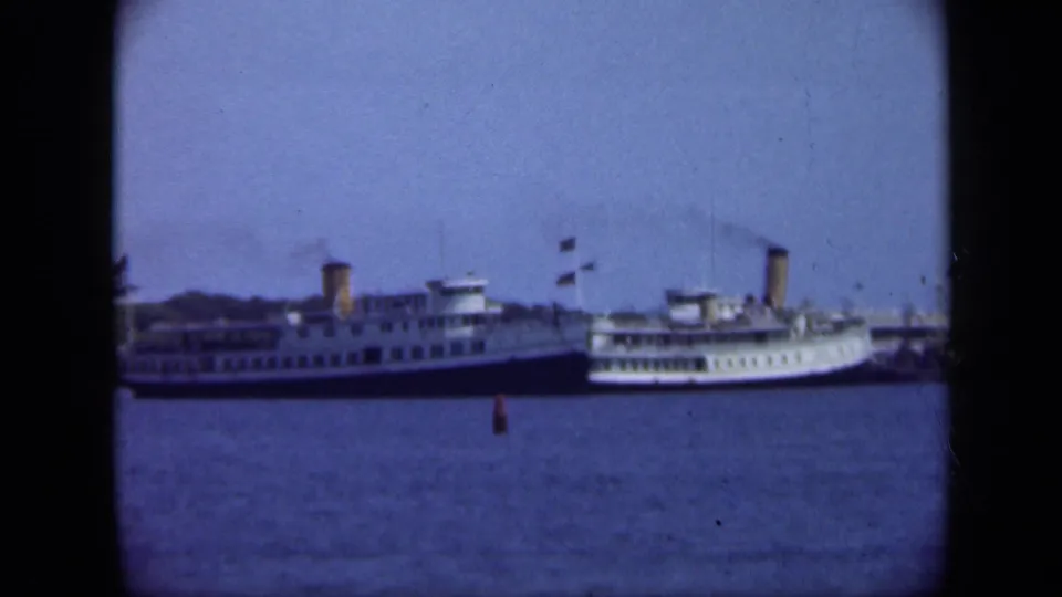1948 Long Island harbor view with two distant passenger steamships, smoking funnels, blue water, and visible 8mm gate edges.
