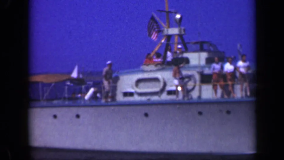 People gather on a white boat deck in 1948 Long Island footage, with the American flag and upper cabin area visible.