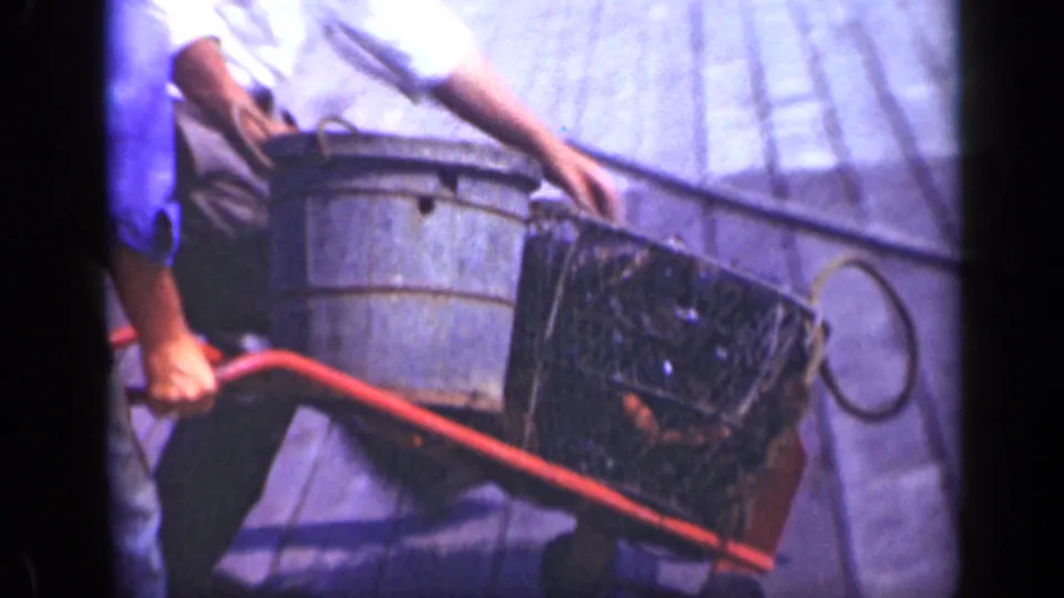 Close 1948 Long Island deck view with a worker, metal bucket, wire basket, and red-handled cart equipment.