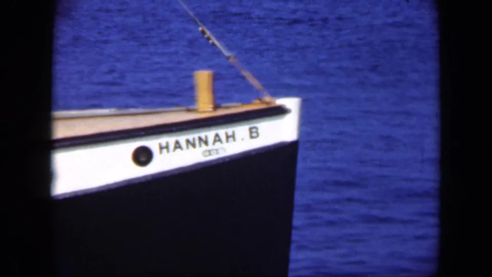 A closer bow view shows the vessel name HANNAH.B with blue water behind it in the Long Island fishing clip.