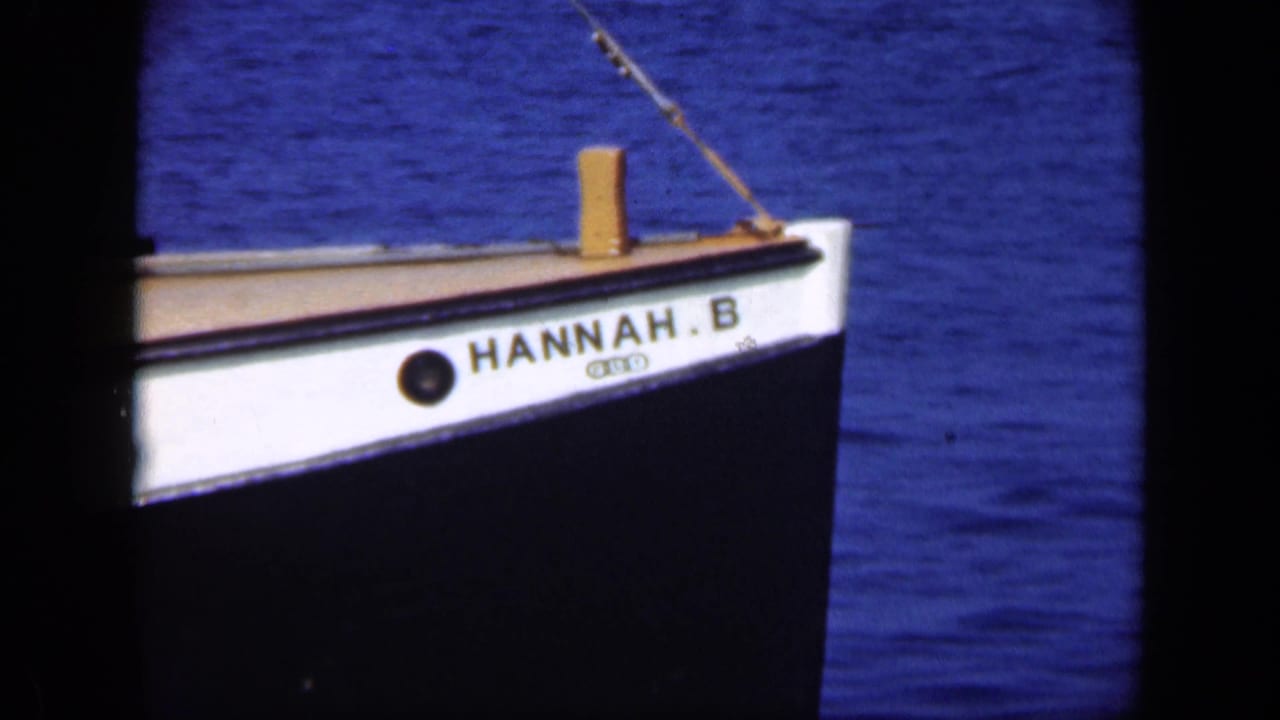 White bow of a small boat named HANNAH.B moving across blue water.