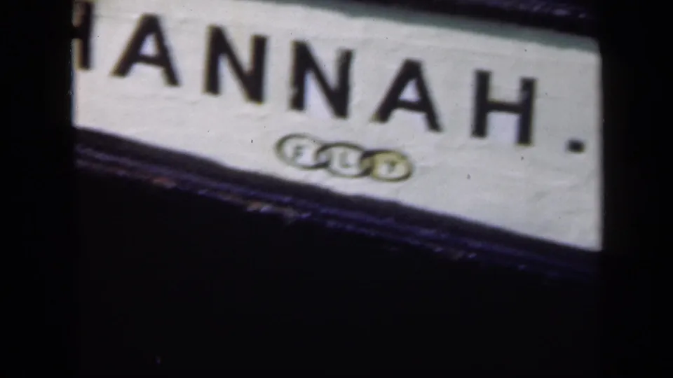 Angled 8mm view of the HANNAH sign, partially cropped at the edge, with a small mark beneath the lettering.