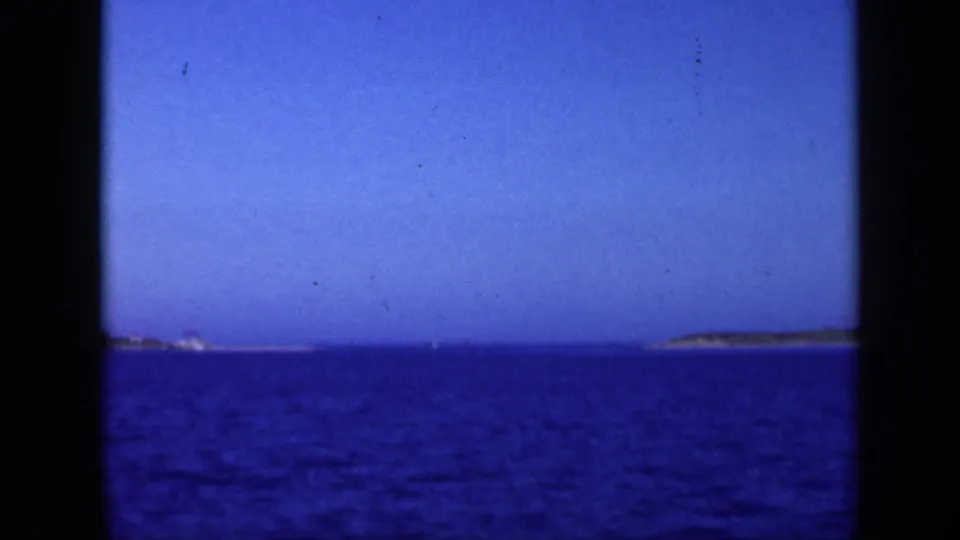 1948 Long Island 8mm frame showing open blue water, a low horizon, and distant landforms under clear sky.