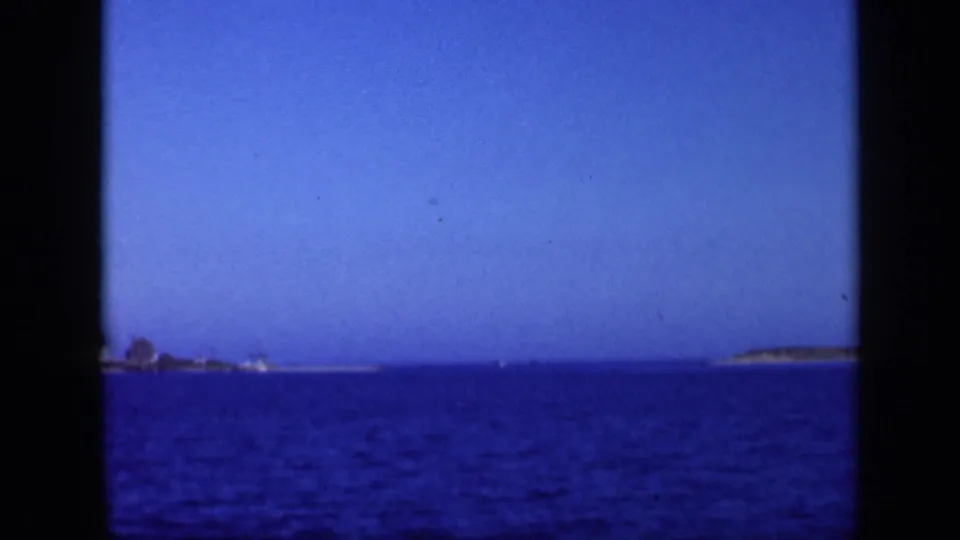 1948 Long Island home-movie frame of blue ocean water, low islands or shoreline, and clear sky through 8mm film edges.