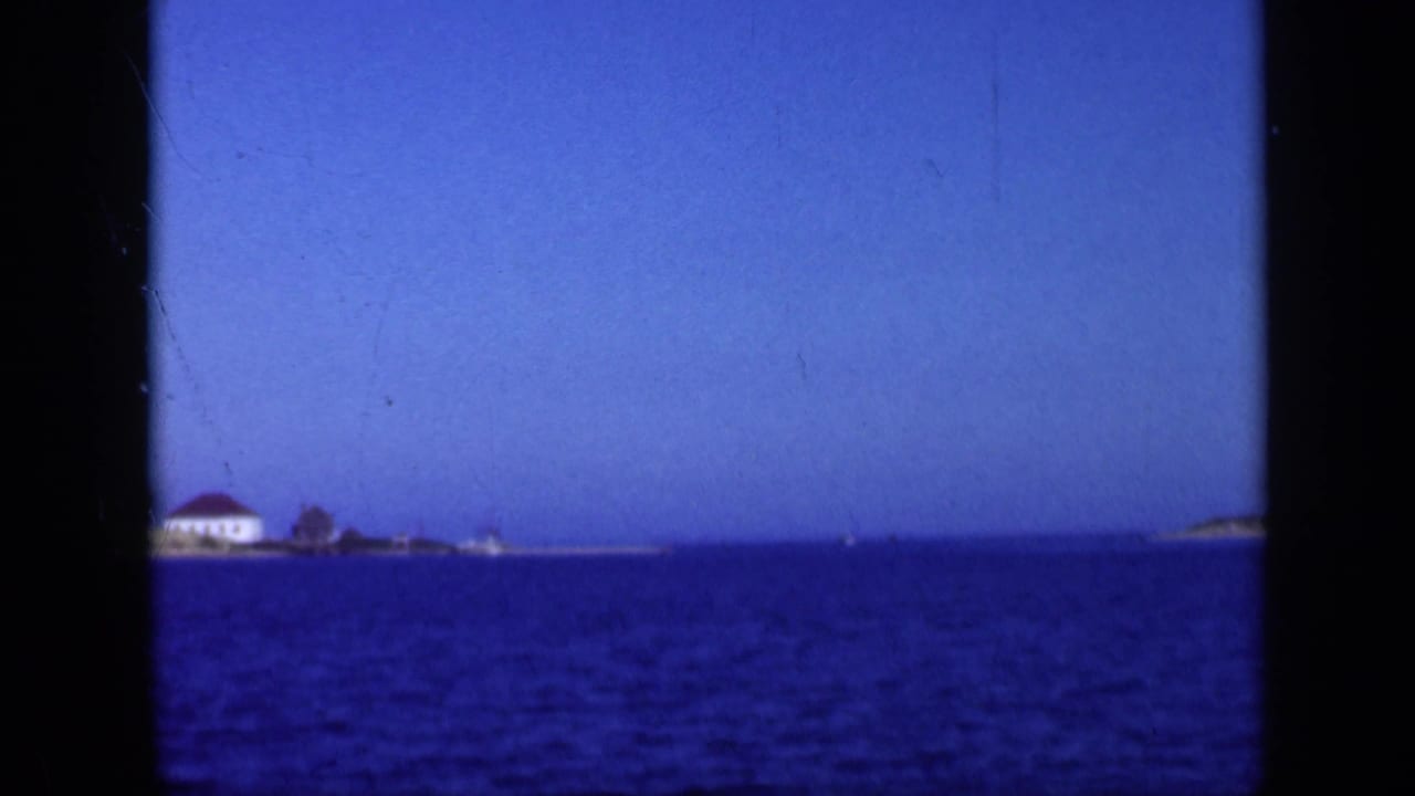 Distant shoreline buildings across blue bay water under a clear sky.