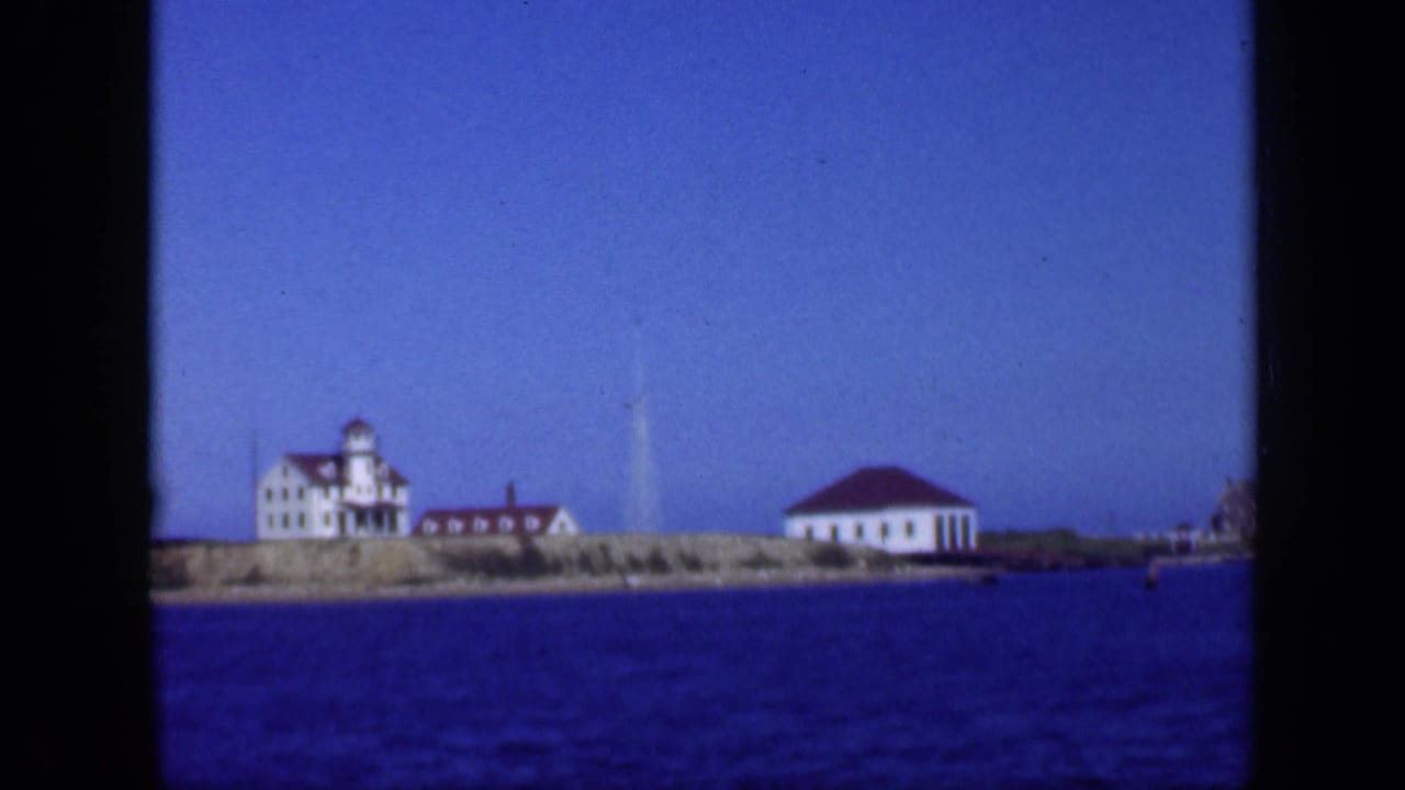 White red-roofed buildings on a low island shoreline across blue water.