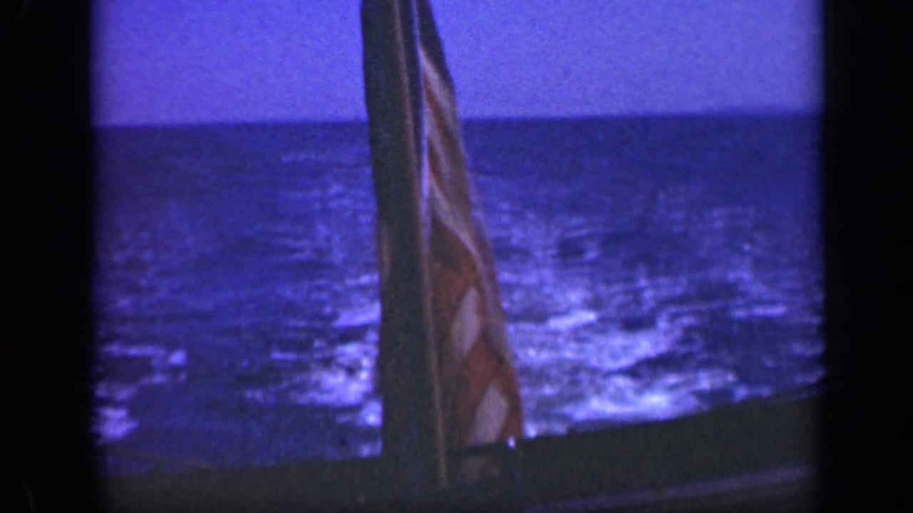 U.S. flag on a boat with blue ocean and horizon behind it.