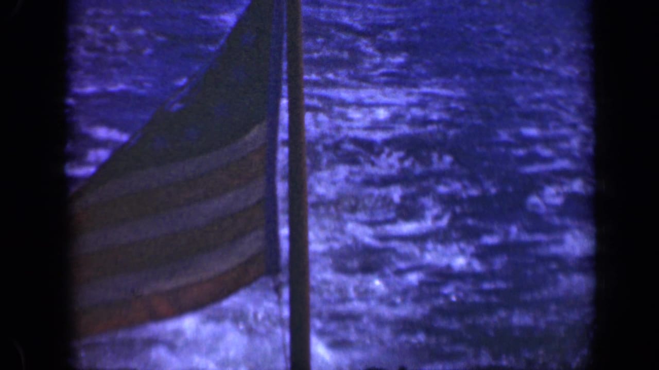U.S. flag on a ship mast with blue water behind it.