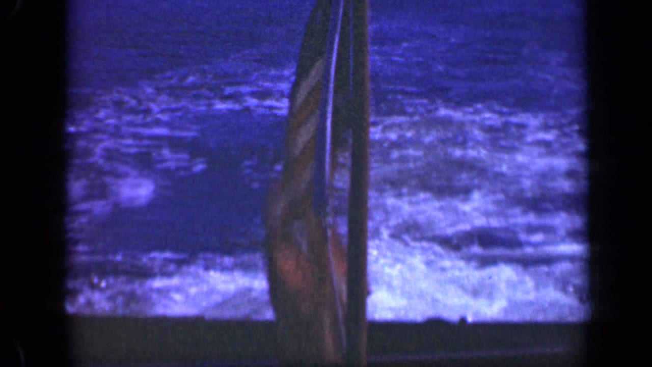 Close view of blue ocean wake with a narrow flag or mast near the center.