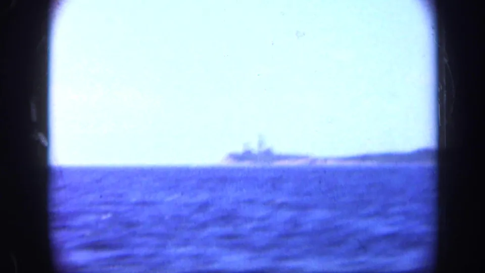 1948 Long Island 8mm view of a distant warship-like vessel on the horizon beyond blue water.