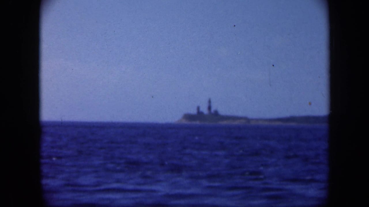 1948 Long Island 8mm frame showing a distant cape and lighthouse-like structure across open blue water.
