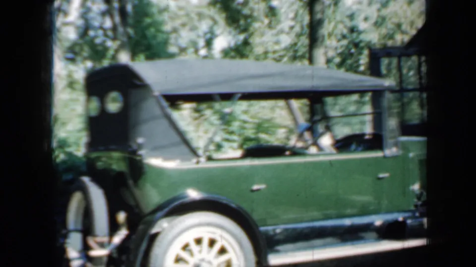 Green classic open-top car with whitewall tires and a black soft top in a wooded Minnesota setting, 1958 metadata supported.
