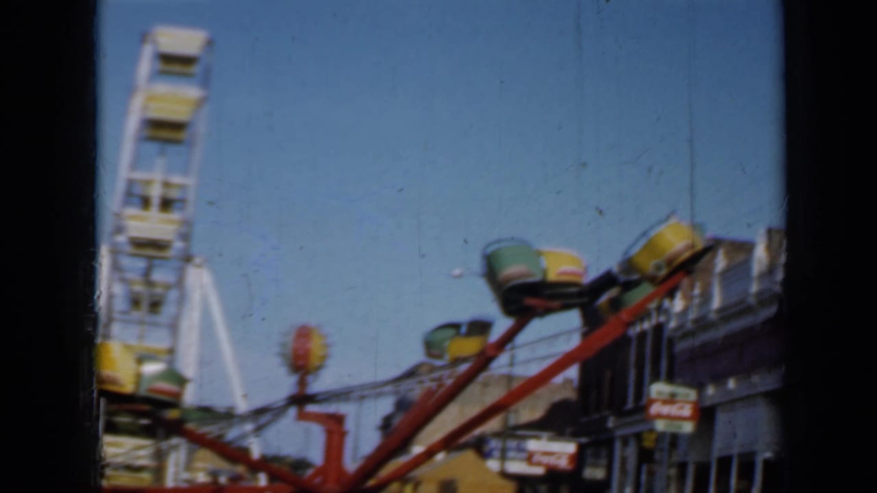 Idle carnival ride with empty seats and a Ferris wheel behind it.