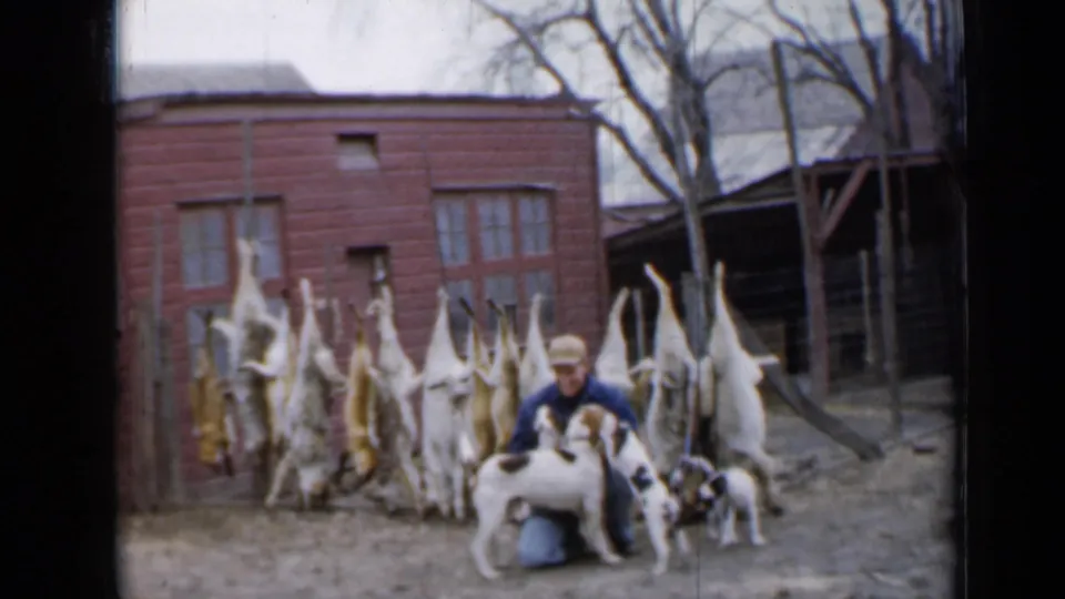 The closing frame shows the man smiling with the mother dog and puppies in a Minnesota farmyard, with hanging game animals behind them.