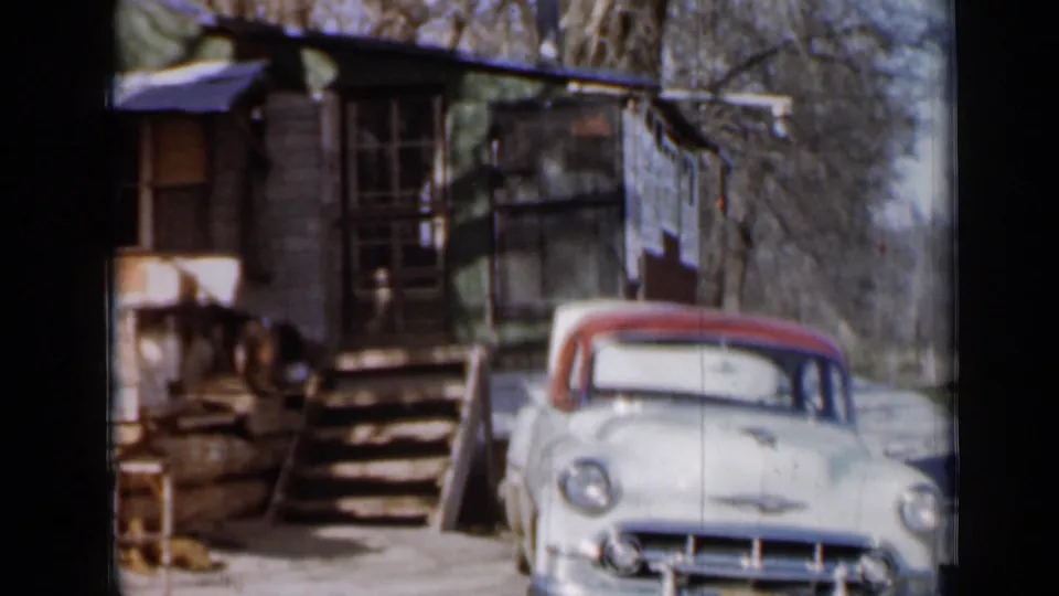 A pale Chevrolet with red roof appears beside a weathered cabin porch and steps in the stated 1958 Minnesota setting.