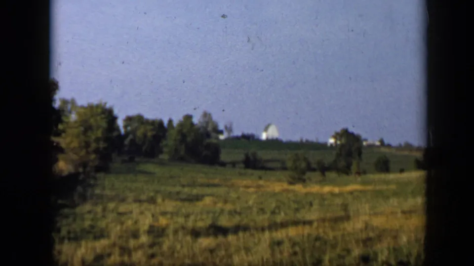 Rural Aledo, Texas pasture with scattered trees and a distant white farm-like structure visible on the horizon.