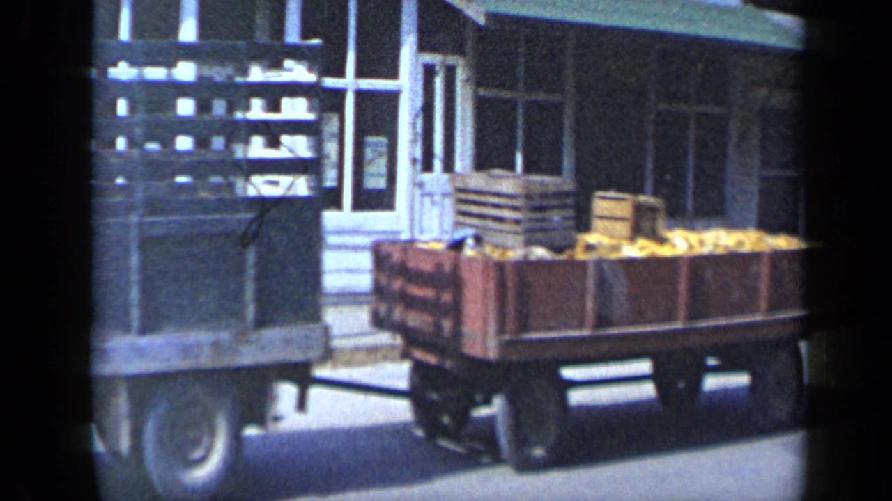 Aledo, Texas 1959 footage shows a wooden wagon loaded with crates and produce moving past storefront windows.