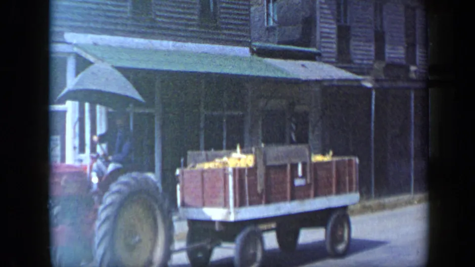A close view shows the tractor wheel and produce wagon passing a storefront in the Aledo, Texas 1959 street scene.