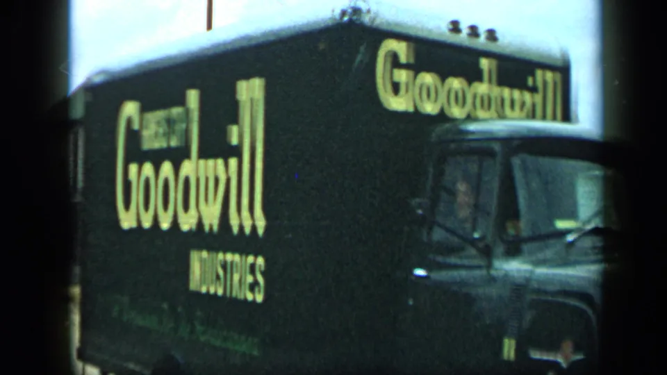 1959 Aledo, Texas frame showing a black Goodwill Industries truck with yellow lettering, partly cropped by the 8mm frame edge.