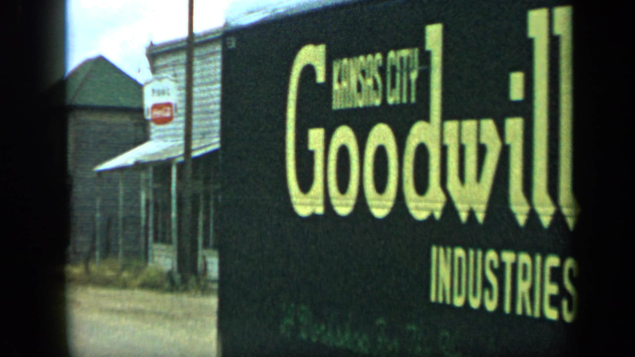 Goodwill Industries sign beside a rural street with storefronts in the background.