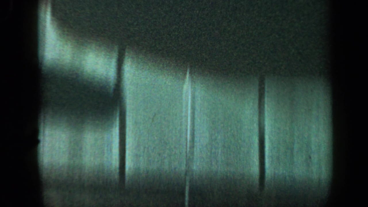 Dark partial frame with blurred siding or wall surface visible at the right.