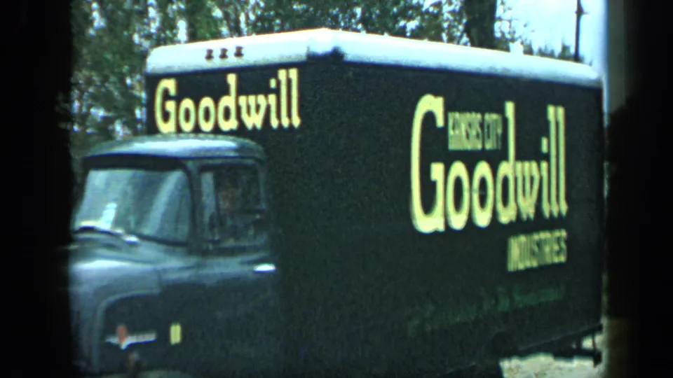 The side of a black Goodwill Industries truck fills the frame, with Kansas City Goodwill Industries lettering visible as it moves past the camera.