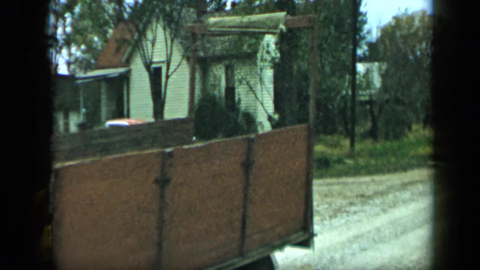 Wooden trailer seen from the side on a residential road in Aledo, Texas, with trees and clapboard homes behind it.