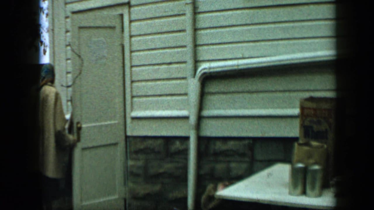 Person near a white door beside a table with boxed groceries and cans.