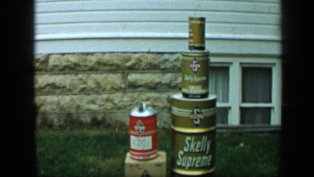 Stacked Skelly Supreme containers beside a red can outside a house.