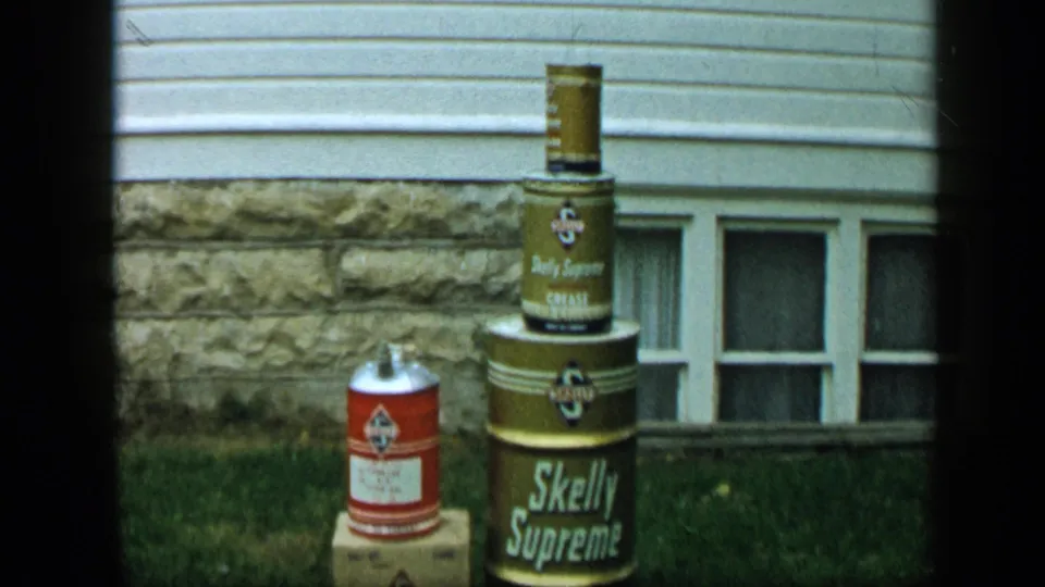 1959 Aledo, Texas home-movie frame showing branded containers outside a house with a basement window behind them.