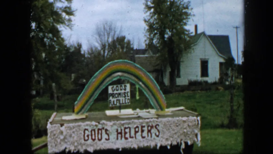 1959 Aledo, Texas home-movie view of the rainbow religious display and GOD'S HELPERS sign near modest houses.