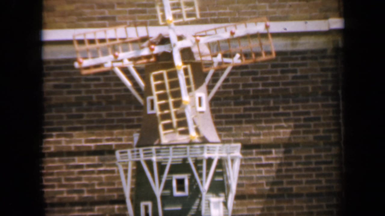 Small decorative windmill mounted against a brick wall.