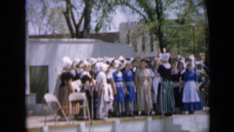 1959 Iowa home-movie frame showing a costumed choir or pageant group standing outdoors in bright daylight.