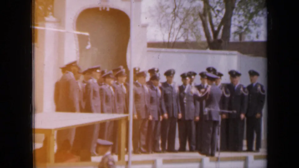 In Iowa, 1959 per metadata, uniformed military personnel stand at attention near a white arched monument during an outdoor ceremony.