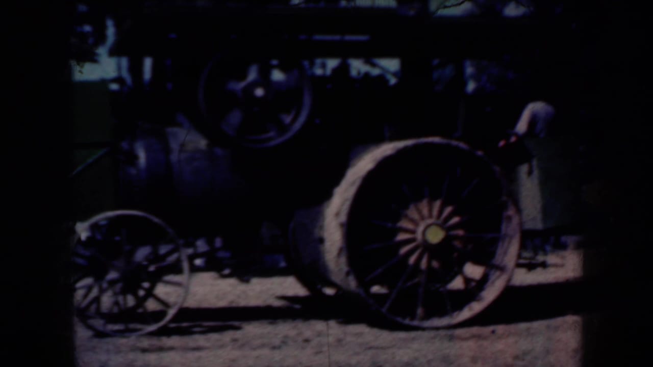 A historic steam tractor appears in a shadowed barnyard view, with large spoked wheels and heavy machinery visible.