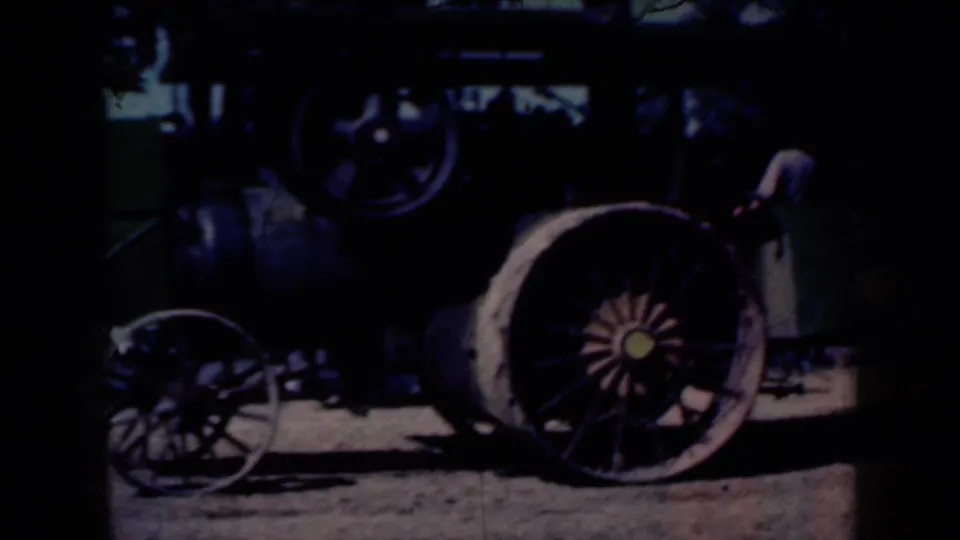 A historic steam tractor appears in a shadowed barnyard view, with large spoked wheels and heavy machinery visible.