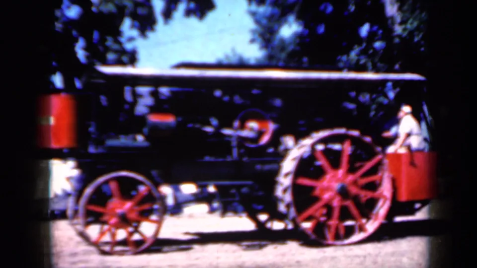1959 Iowa 8mm frame with the red-wheeled steam tractor filling the view and a person partly visible near the rear platform.