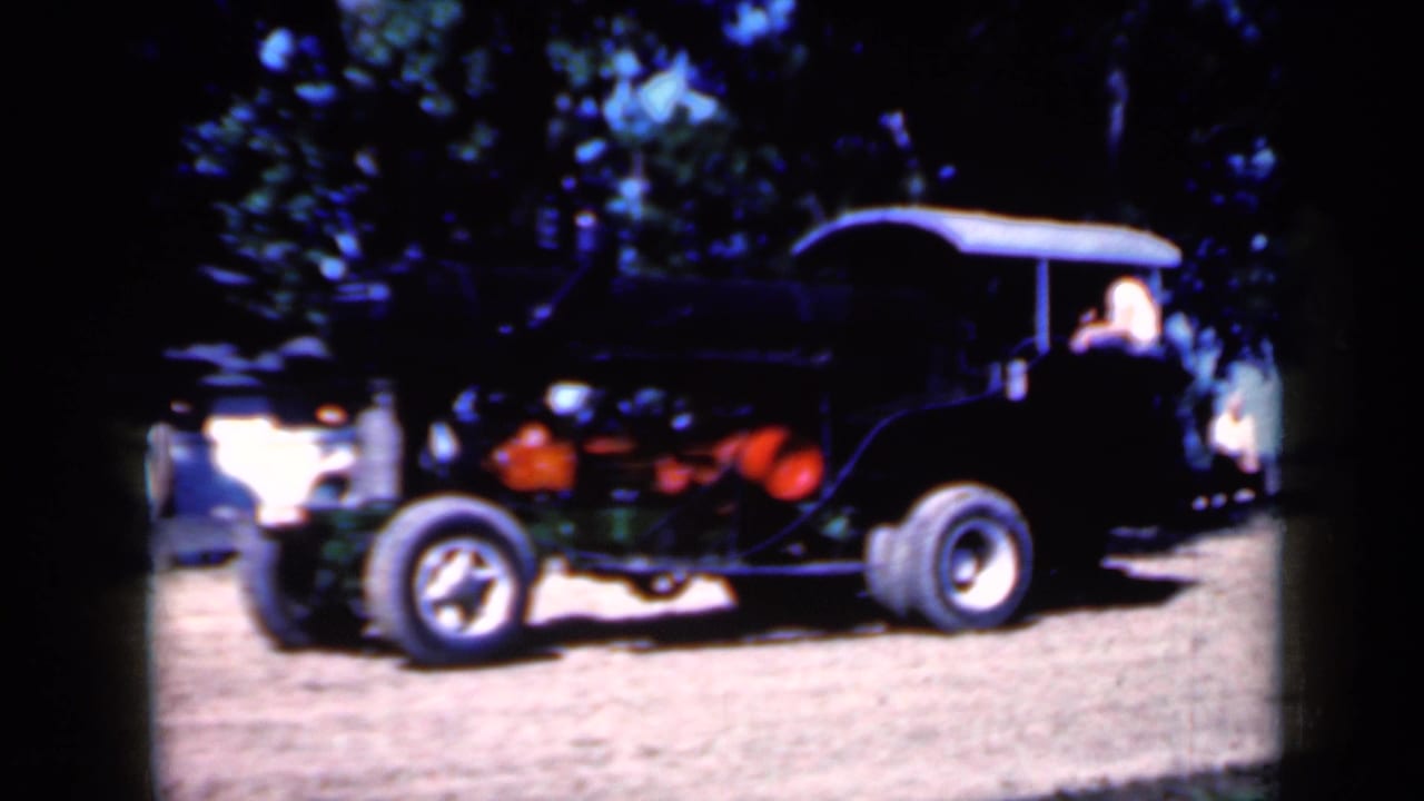 Side view of a canopy-covered steam tractor with a person seated near the rear.