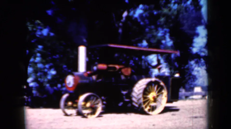 A later frame shows a vintage steam tractor with a tall smokestack, canopy, spoked wheels, and trees in the background in Iowa.