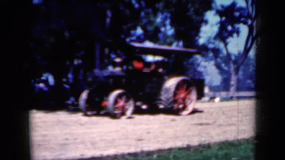A darker 1959 Iowa frame shows the steam traction engine from the side, with red wheel detail and shaded trees in the background.