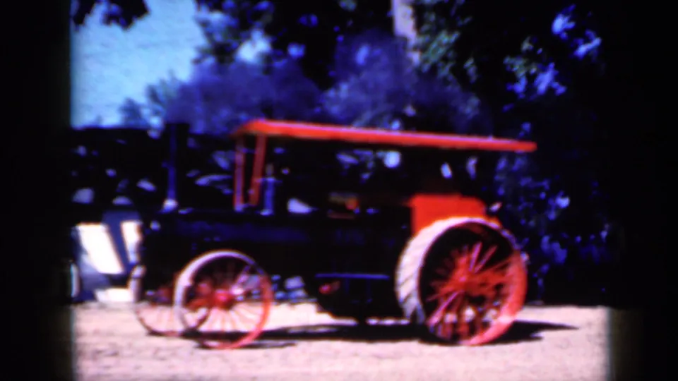Final frame of the 1959 Iowa 8mm clip showing the parked steam tractor under trees with benches and people nearby.